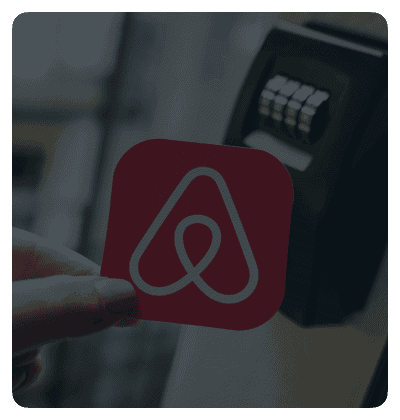 Hand holding Airbnb logo near a keypad lock.