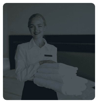 Housekeeper holding folded towels in a hotel room.