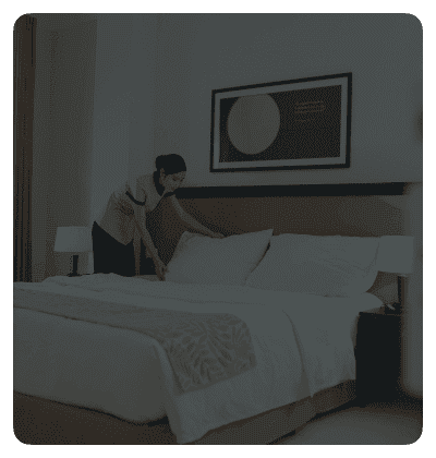 Hotel staff preparing a bed.